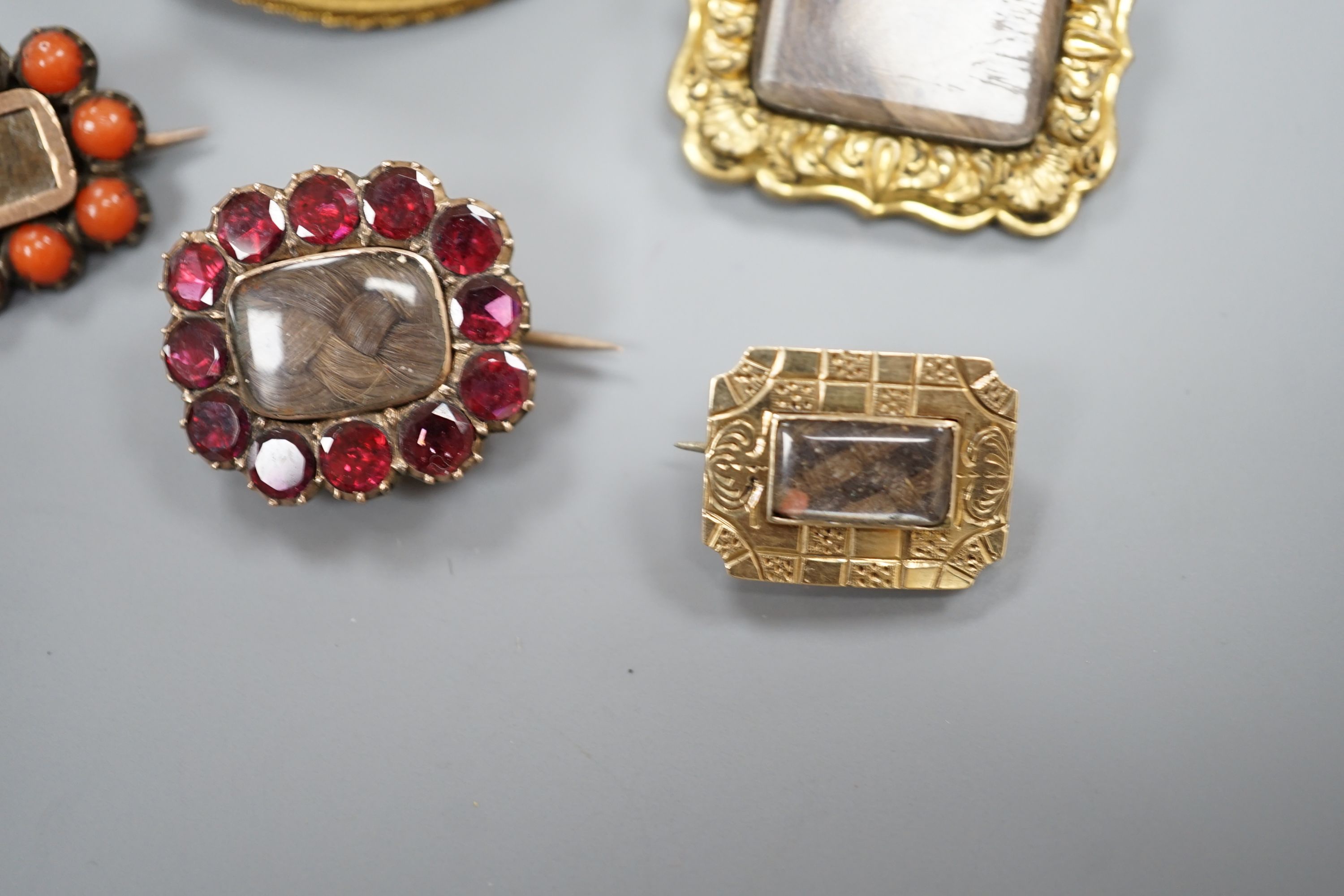 Two 19th century gilt metal and plaited hair set mourning brooches, two other mourning brooches and an oval pinchbeck brooch, largest 34mm.